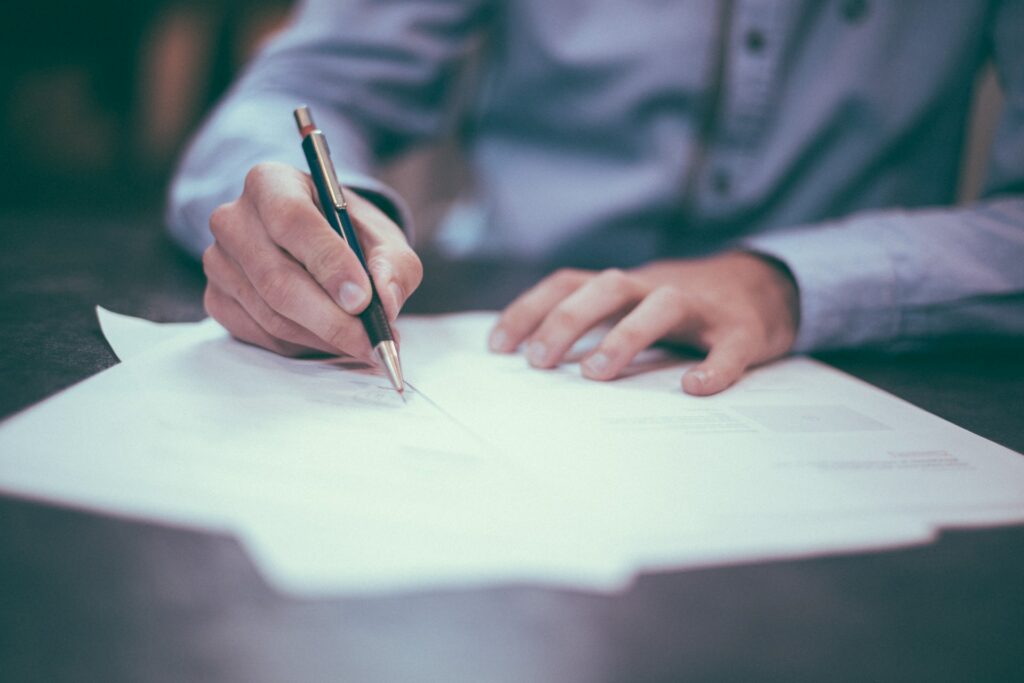Un homme signant les feuilles d'un contrat sur une table